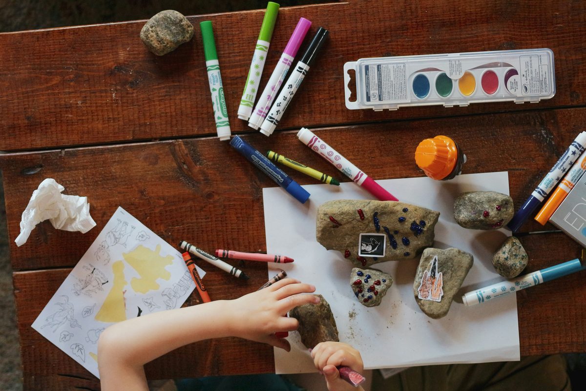 A craft table: markers, watercolors and painted stones