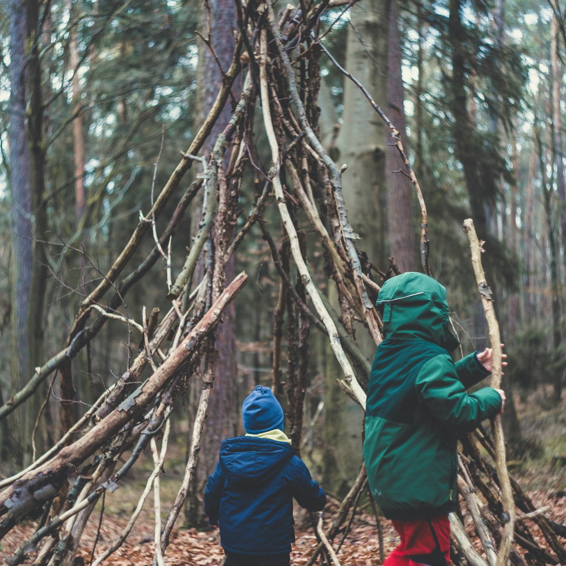 Two children building a stick fort in the woods