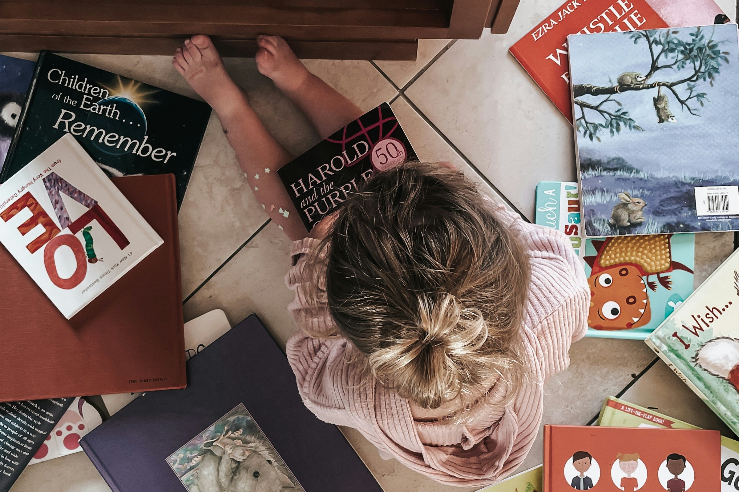 A child lying on the floor surrounded by picture books