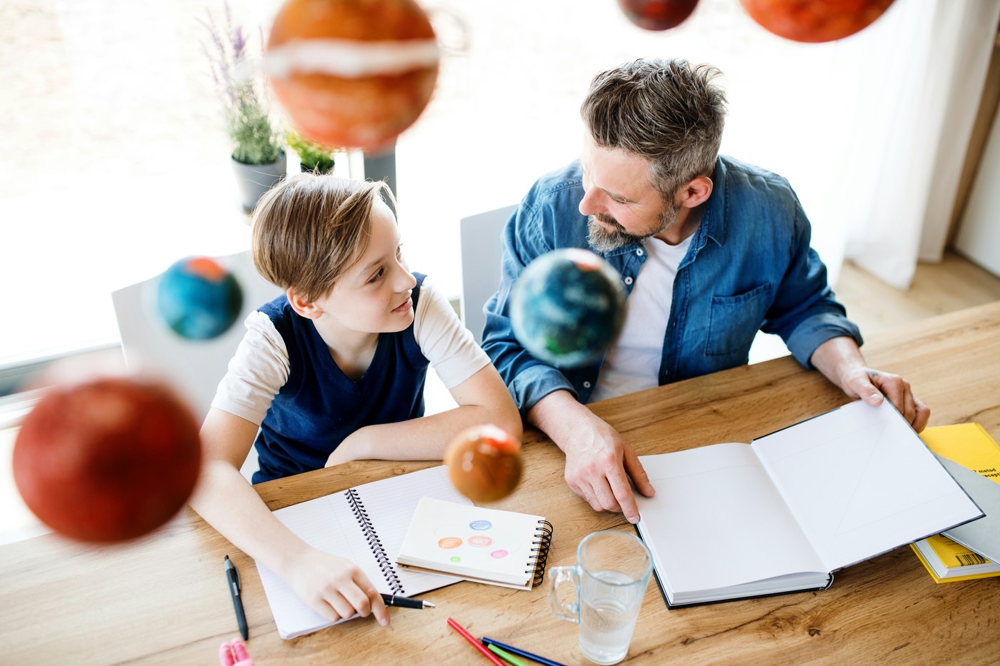 A father and child at the kitchen table with a science notebook open